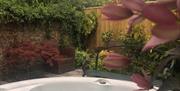 An outdoor yard area with bubbling hot tub, bench and planters at Bright Moments, Beverley, East Yorkshire.