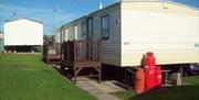 The rear of a static caravan, gas bottles and decked entrances at Thornwick Bay Private Hire Caravan in East Yorkshire.