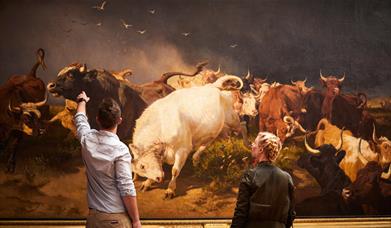 Two people in front of an artwork featuring a herd of cattle, in East Yorkshire