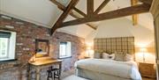 A double bedroom with cottage beams and feature brick wall at Bolthole Cottage in East Yorkshire.