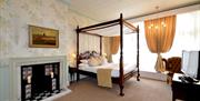 A spacious four poster double bedroom with fireplace at Cave Castle in East Yorkshire.