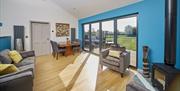 A blue living room and dining area with log burner and bifold doors at North Star Sanctum in East Yorkshire.
