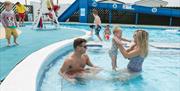 A family of 3 playing in a outdoor pool at Barmston Beach in East Yorkshire.
