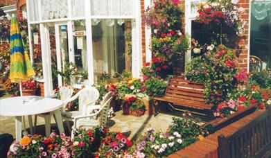 Lots of flowers with a table and chairs at the front of Spinnaker Guest House in East Yorkshire.