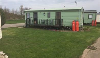 A static caravan side view, with deck and gas bottles at Thornwick Bay Private Hire Caravans in East Yorkshire.