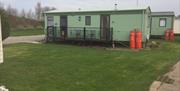 A static caravan side view, with deck and gas bottles at Thornwick Bay Private Hire Caravans in East Yorkshire.