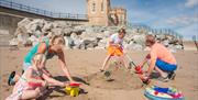 A family making sandcastles on the beach in front of Pier Towers at Withernsea, in East Yorkshire.