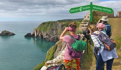 A group of walkers look out to sea from a clifftop position at Berry Head Nature Reserve, Brixham