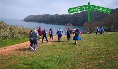 A group of people walking along the South West Coast Path between Paignton and Brixham.