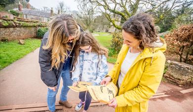 Two adults and a child looking at a map in outside green setting