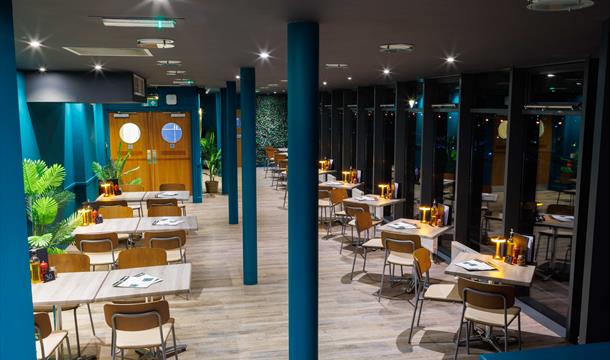 Pizza al Teatro pre theatre dining area, green walls and poles, with tables and chairs set for dinner service overlooking the Marina