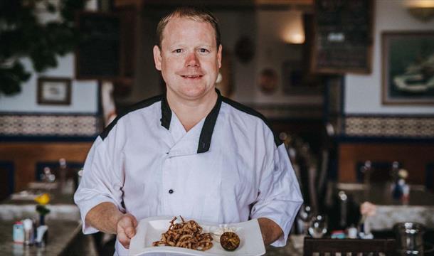 Head Chef carrying a dish of squid at Number 7 Fish Bistro Torquay