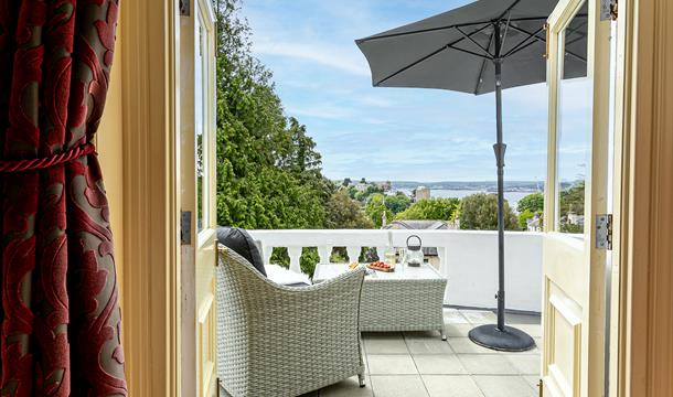 View through french doors of Vomero apartment onto private balcony with rattan furniture, parasol and sea view.
Sea view from the balcony at Vomero Ho