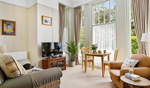 Lounge area of Roma apartment with sofa, dining table and large windows