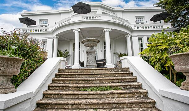 Exterior view of Vomero Holiday Apartments in Torquay, a historic Grade II listed villa with sea views, tiered gardens, balconies, and private terrace