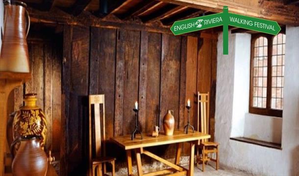 The interior of Kirkham House in Paignton, with wooden furniture and ceramic storage jars, wood panelled walls.