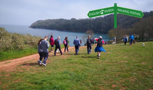 A group of people walking along the South West Coast Path between Paignton and Brixham.