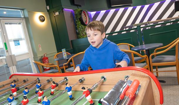 Child playing Shuffleboard in the Saltwater Kitchen, Terrace & Bar