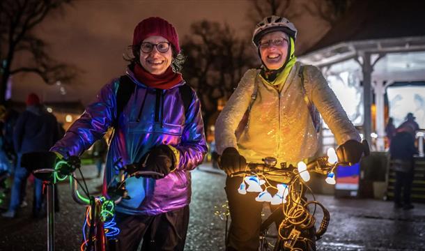 Two women with glowed up bikes and bright clothing on a dark night