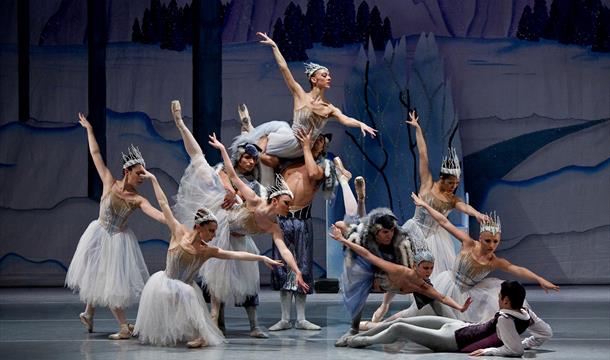 dancers performing on stage dressed mostly in white and wearing sparkly and spiky crowns