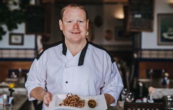 Head Chef carrying a dish of squid at Number 7 Fish Bistro Torquay