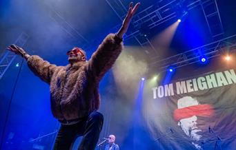 An Evening with Tom Meighan – The Original Voice of Kasabian Palace Theatre Paignton picture of Tom Meighan on stage in a fake fur bomber jacket