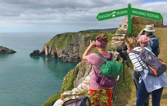 A group of walkers look out to sea from a clifftop position at Berry Head Nature Reserve, Brixham