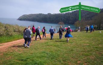A group of people walking along the South West Coast Path between Paignton and Brixham.