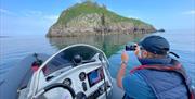 Torquay Watersports coastal wildlife boat tour - a passenger takes a photo of Thatchers Rock from a boat at sea in Tor Bay, English Riviera