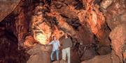 Two adults stand in one of the underground caves at Kents Cavern Prehistoric Caves in Torquay, English Riviera.