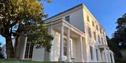 Photo of the exterior of Greenway House and a selection of photos sitting on a piano