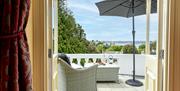 View through french doors of Vomero apartment onto private balcony with rattan furniture, parasol and sea view