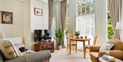 Lounge area of Roma apartment with sofa, dining table and large windows