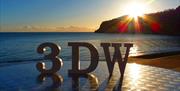 A wooden 3, D and W on a table looking out to sea at sunrise