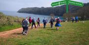 A group of people walking along the South West Coast Path between Paignton and Brixham.