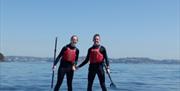 2 persons standing on a paddleboard, Coastal Paddleboard Adventure, Reach Outdoors