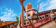 a young girl enjoy a play park swing at crealy theme park