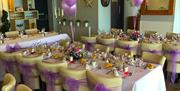 Inside tables set up for a wedding with lilac bows on the chairs and lots of lilac accessories