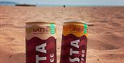 Costa Coffee latte cans on the beach at Goodrington Sands, Devon.