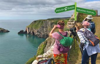 A group of walkers look out to sea from a clifftop position at Berry Head Nature Reserve, Brixham