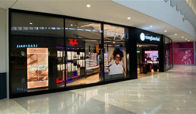 Outside Sunglass Hut at The O2. A glass shopfront looking into a huge selection of sunglasses.