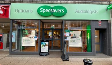 Outside Specsavers, showing a pale green shop front with a lovely inside area.