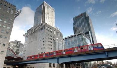 Docklands Light Railway train moves along a bridge among the skyscrapers of Canary Wharf.