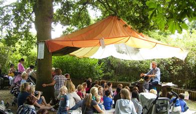 Storyteller and group of families under an oak tree