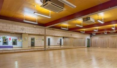 Inside one of Thamesmere Leisure Centre's fitness halls, showing a brown room with mirrors, good lighting and air conditioning.