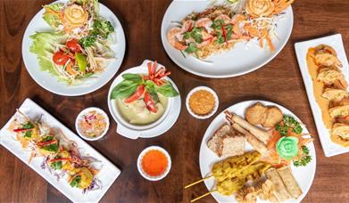 Table set with Kathi Thai Kitchen specialities including appetisers platter, papaya salad, green curry and more.