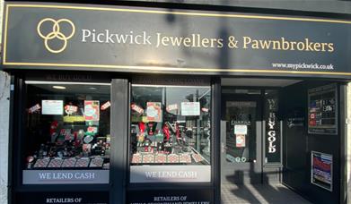 Outside Pickwick Jewellers & Pawnbrokers in Eltham. A black and gold designed shop with a selection of jewellery in the window.