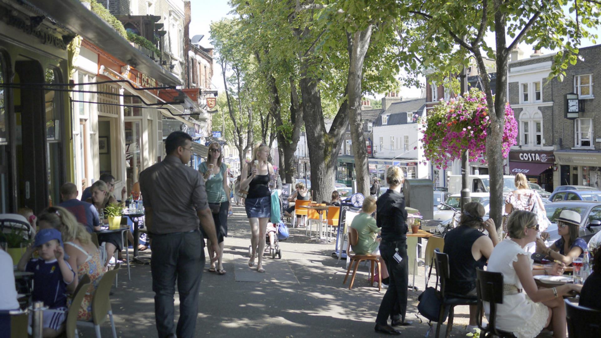 People in the streets of Blackheath Village,, Greenwich, eating and drinking at outdoor tables.