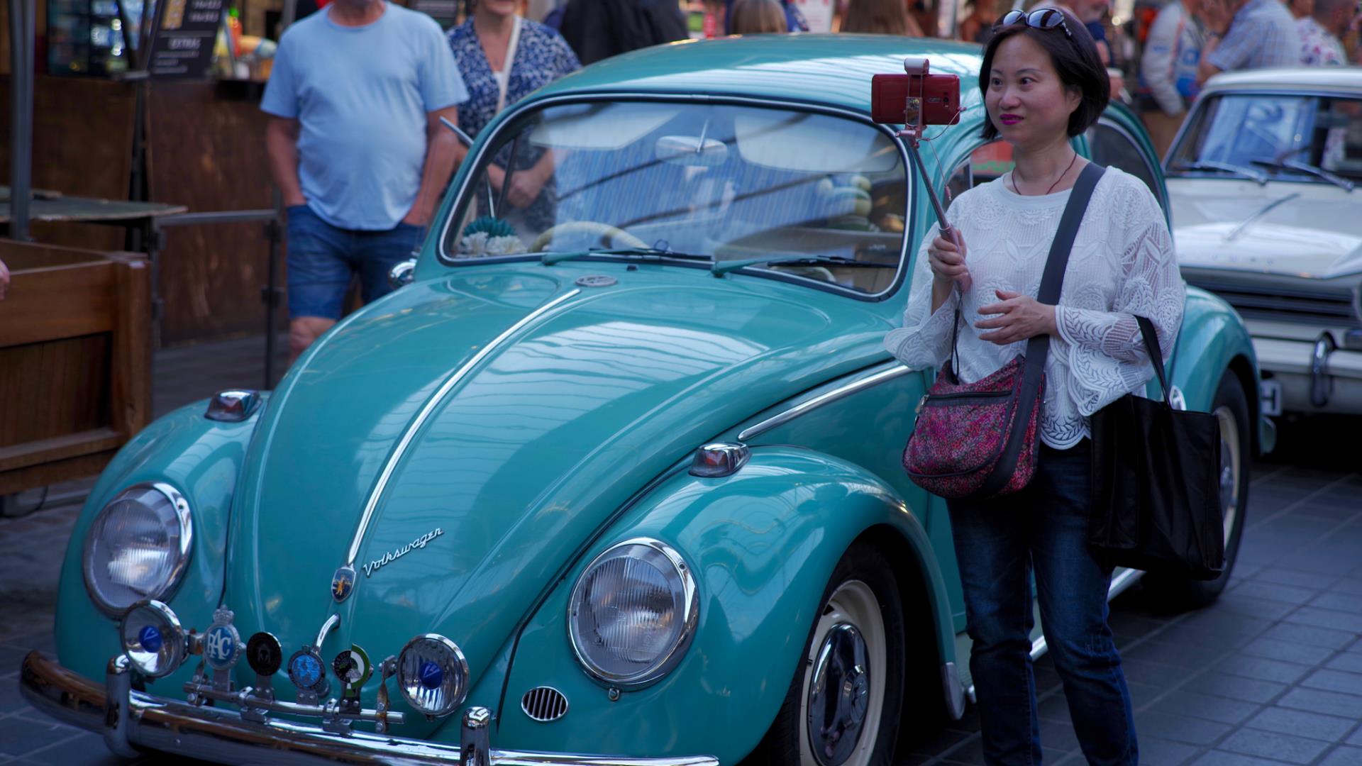 A woman poses with a classic car at Park It in the Market at Greenwich Market.