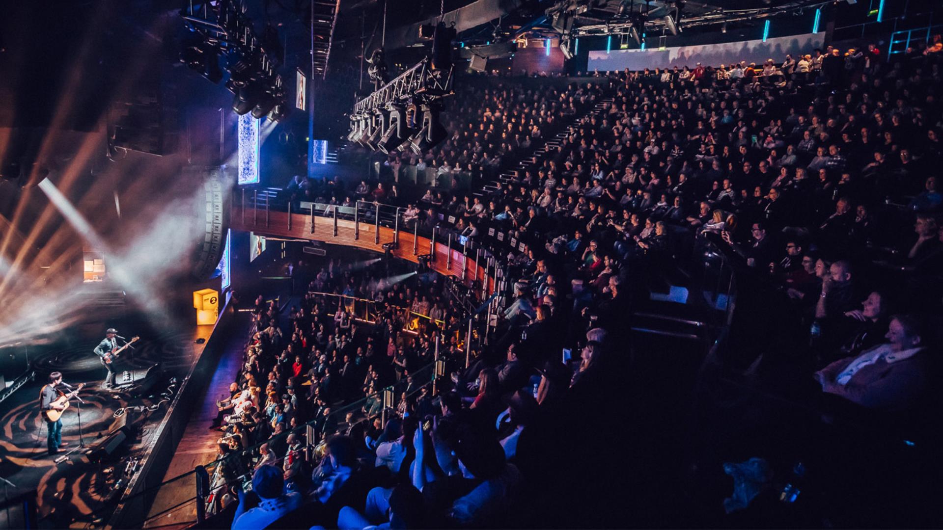 A band perform on stage in front of a huge crowd at indigo at The O2 in Greenwich.